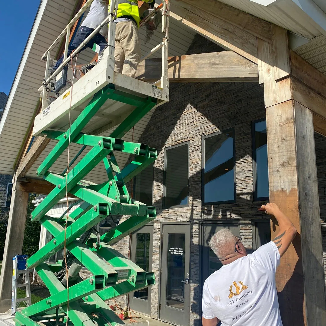 Crew painting a commercial building exterior from a scissor lift