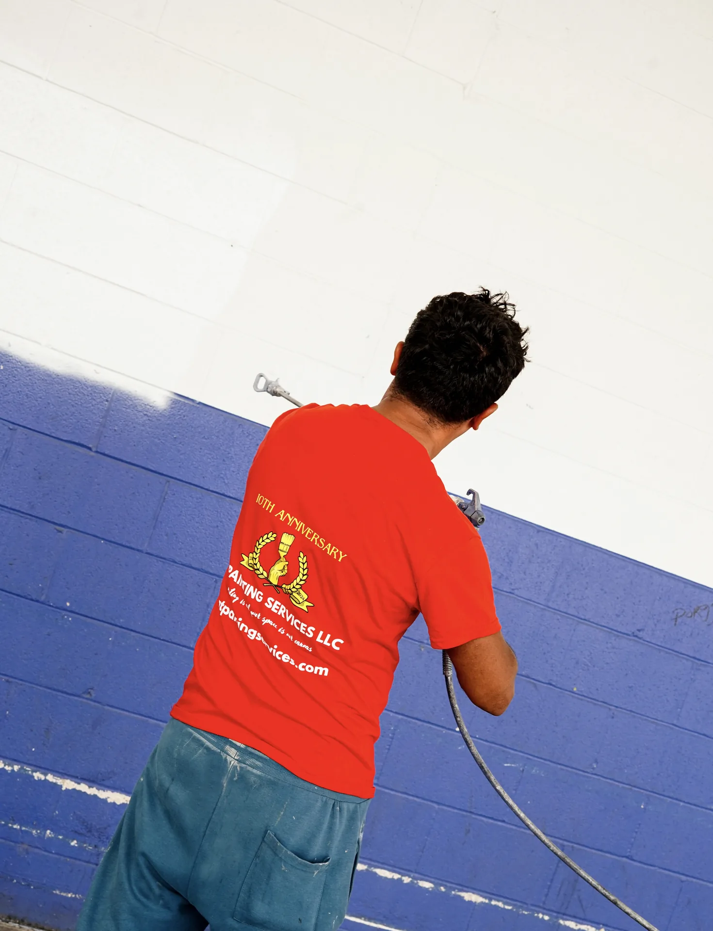 GT Painting Services crew member spray-painting a commercial wall
